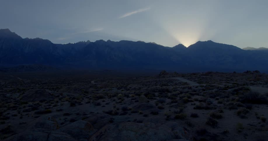 The sun sets over a rocky desert plain
