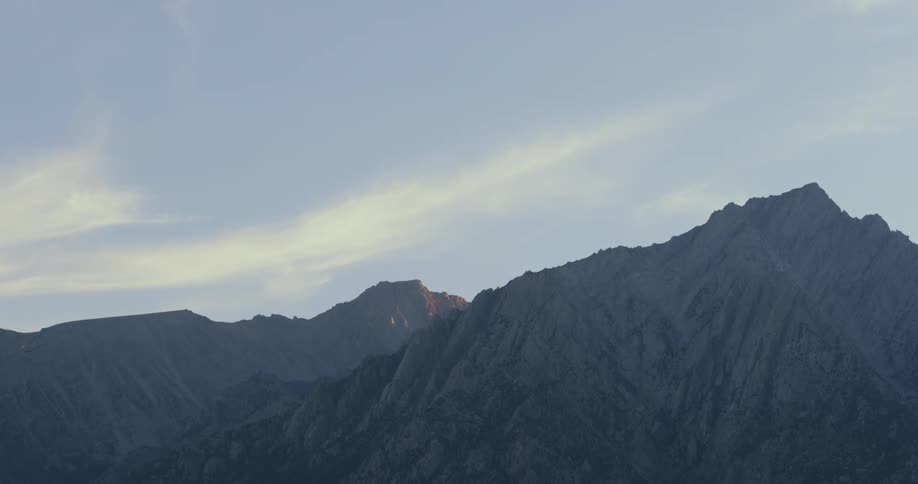 A mountain range is viewed at dawn