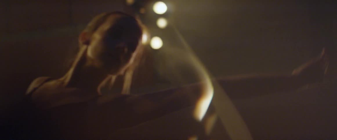 A woman dances slowly under lights