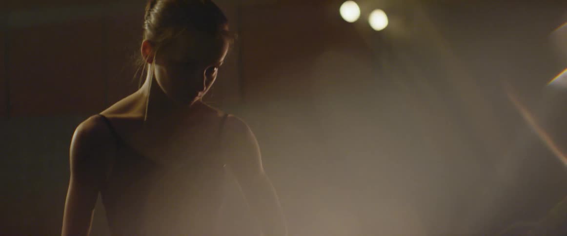 A dancer stands under a light