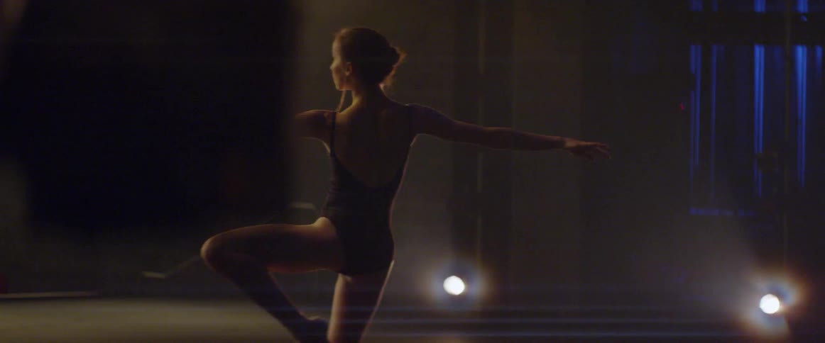 A woman in a leotard dances on stage