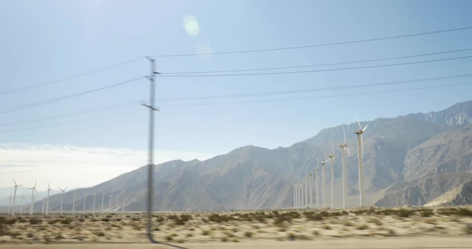 View from a road of some wind turbines near a large mountain