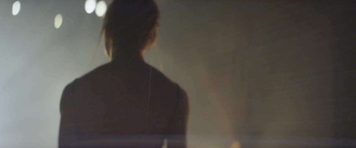 A dancer walks on stage and looks up at the lights