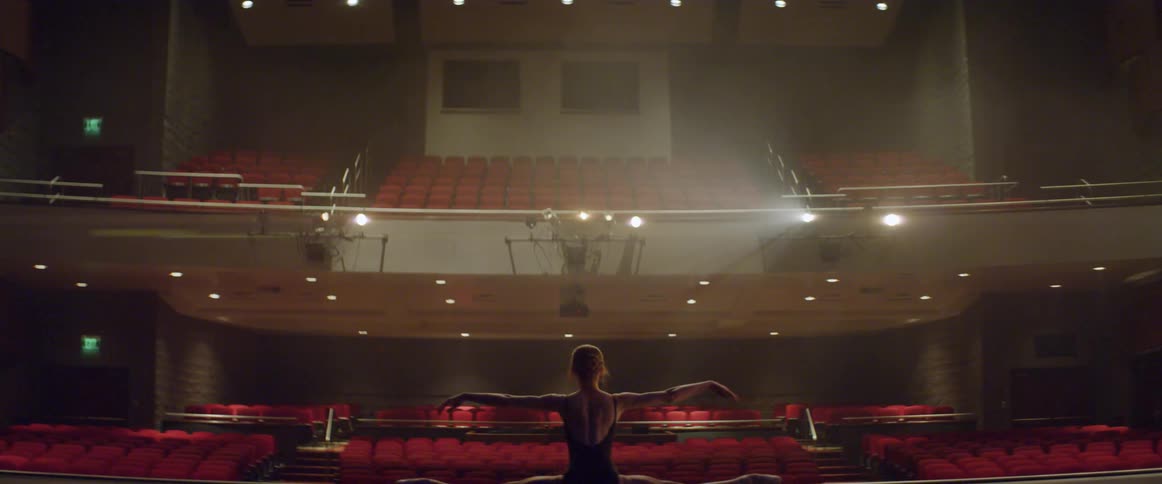 A woman stretches on stage