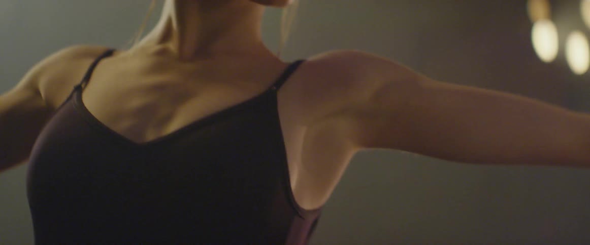 A dancer stretches and practices on stage with lights shining