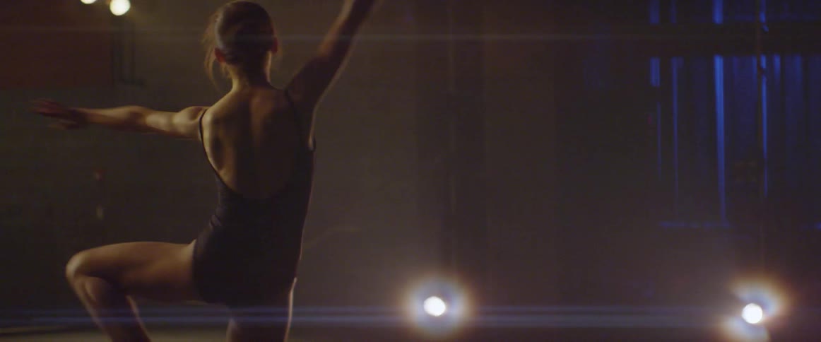 A ballet dancer practices on stage in a theater under the lights