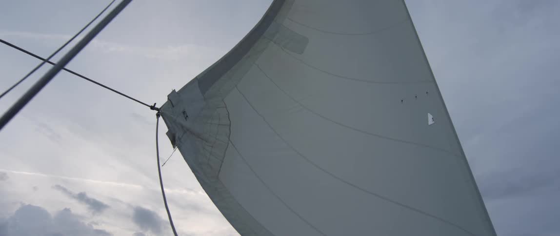 A sailboat sail is blowing in the wind