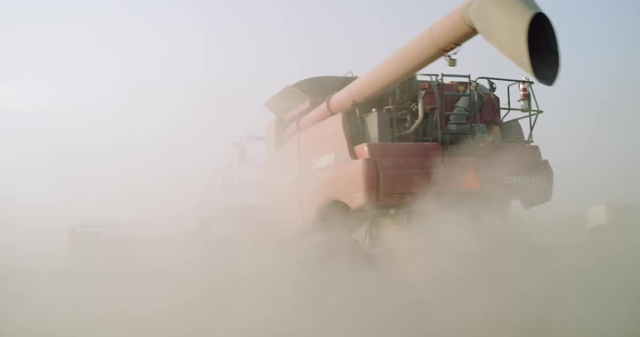 A large tractor is spraying fertilizer on a crap