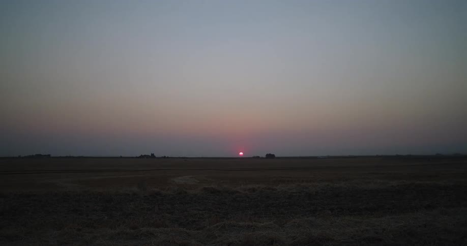 The sun is setting over a large plain
