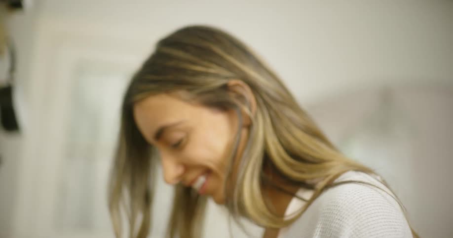 A woman is cutting food with a knife while talking and smiling