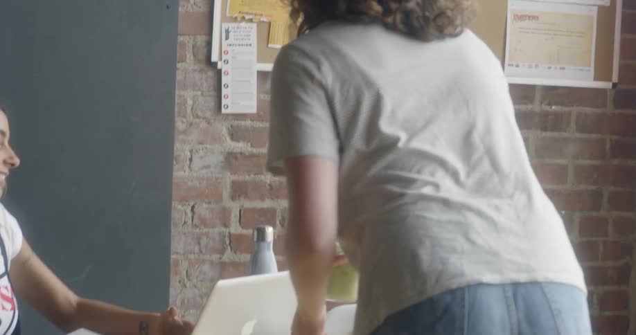 A plate of food is being carried across a lobby to a woman at a table with a laptop