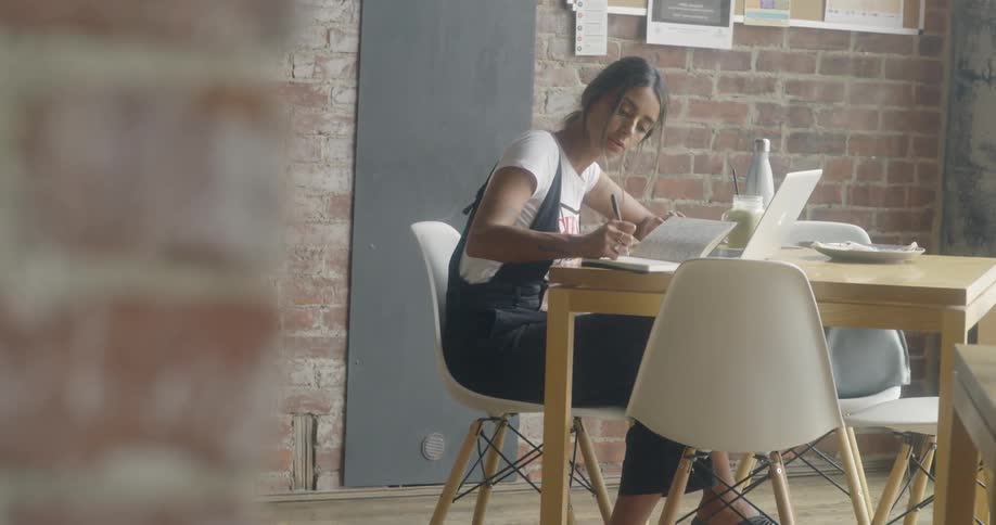 Woman sits at a table writing