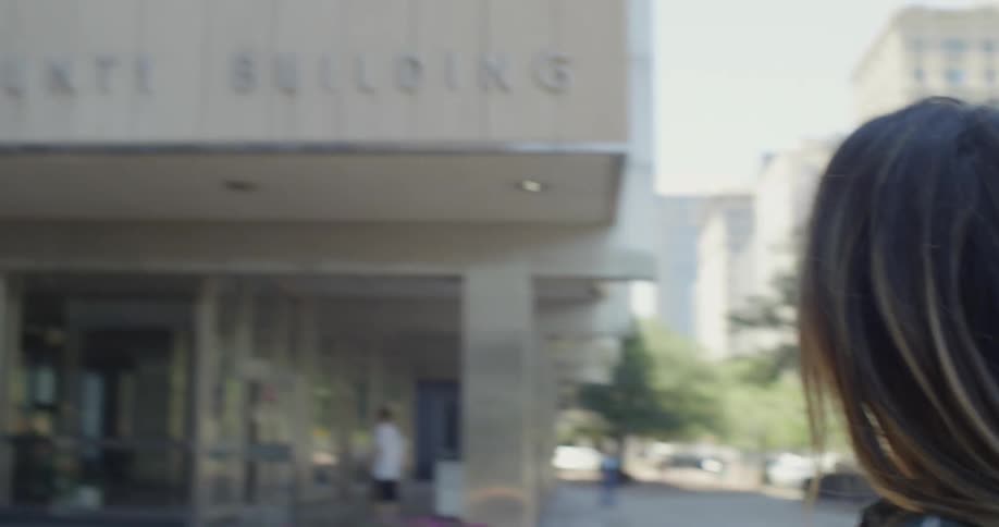 A woman stands outside on a city sidewalk