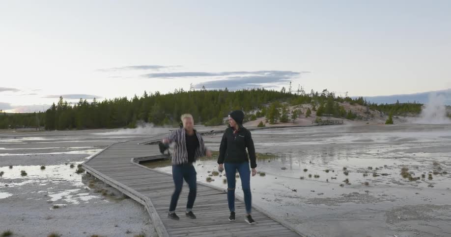 Man and woman walking down a boardwalk as the man jumps