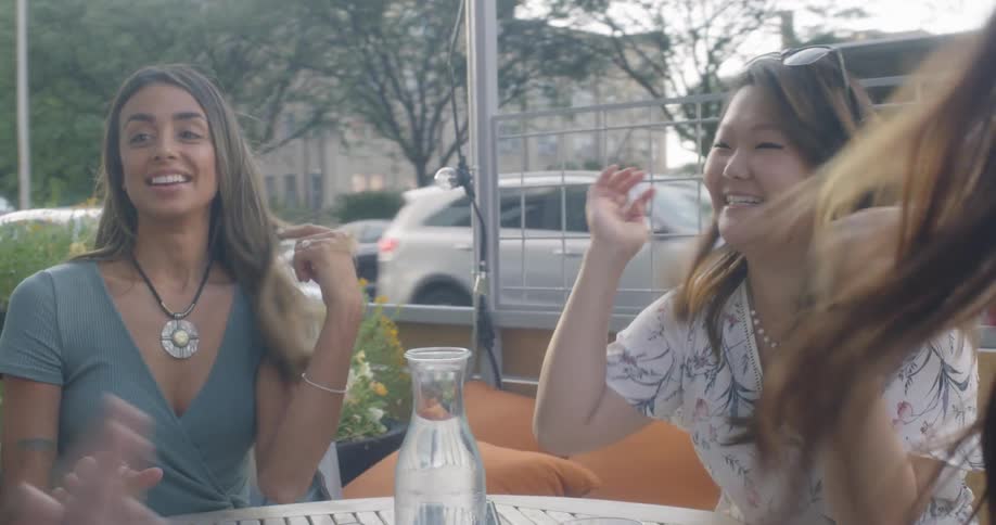 Female friends sit at a restaurant table on the patio