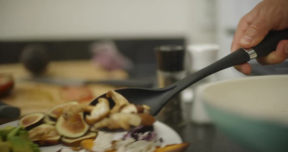 A woman and man are plating food they have prepared in their kitchen