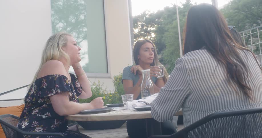 Four women sit at an outdoor table talking