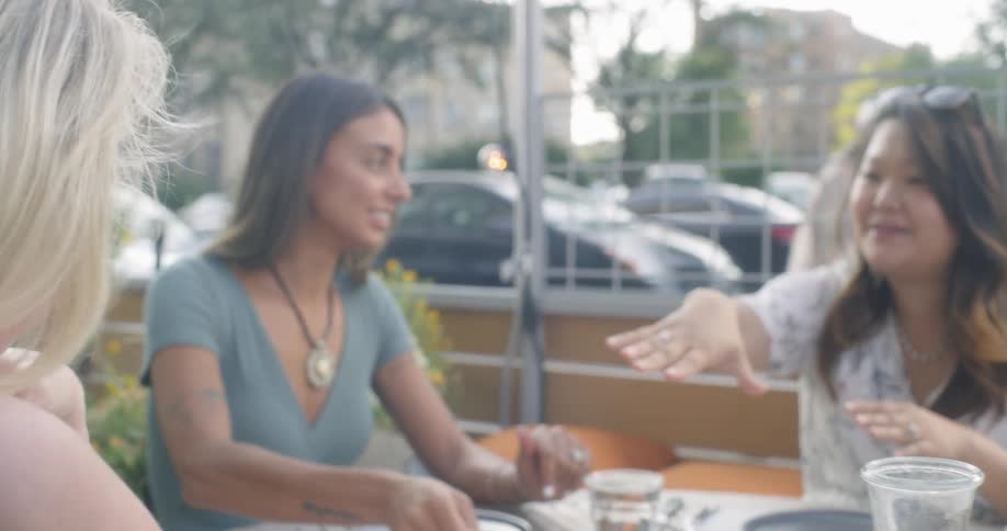 A waiter places a plate of food on the table as women admire a ring
