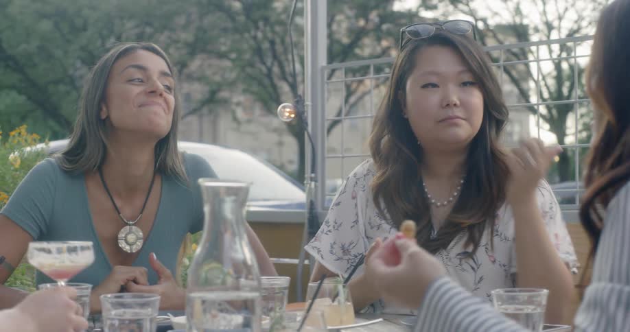Four women sit at an outdoor table talking