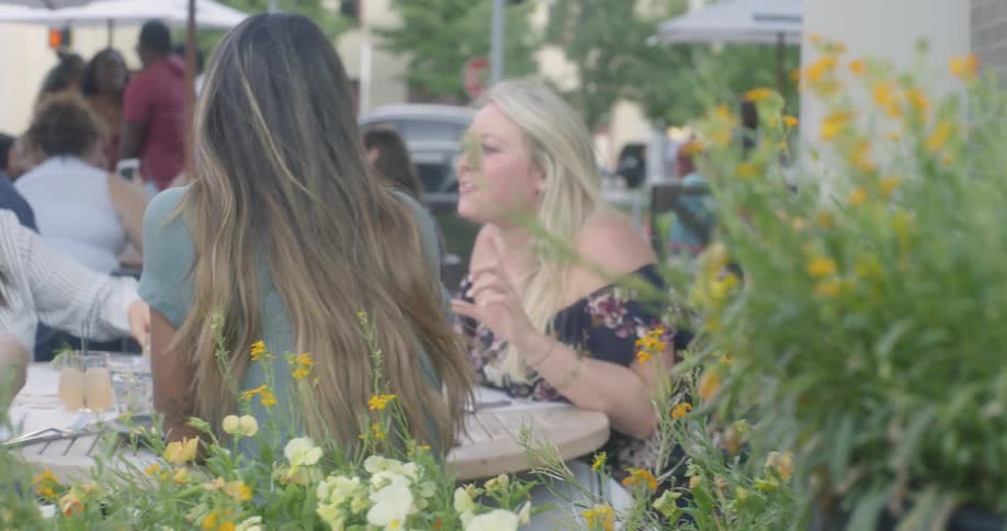 A group of women dine at a cafe table outside a restaurant