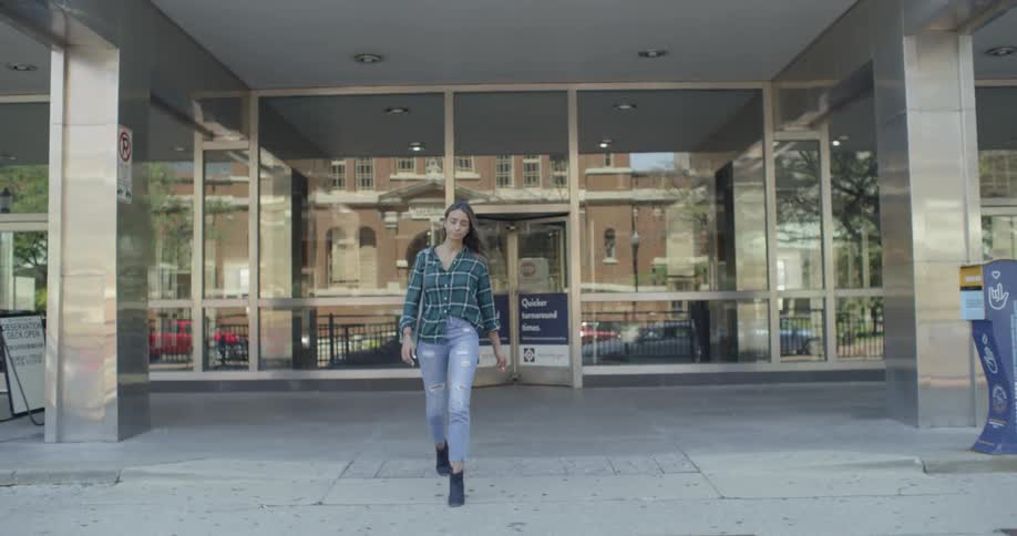 A woman is walking out of a building and towards the street