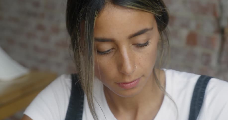 A woman is writing in a notebook as she sits in a cafe during the day