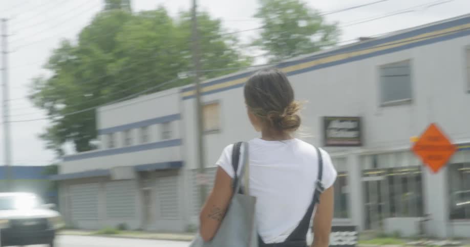 Woman turns a corner and walks into a building