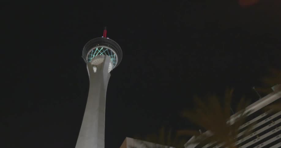 A large lighted tower looms over a downtown part of a city