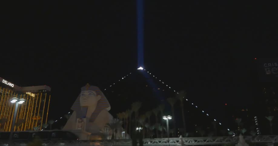 View of a casino with a pyramid nearby shining a light into the night sky