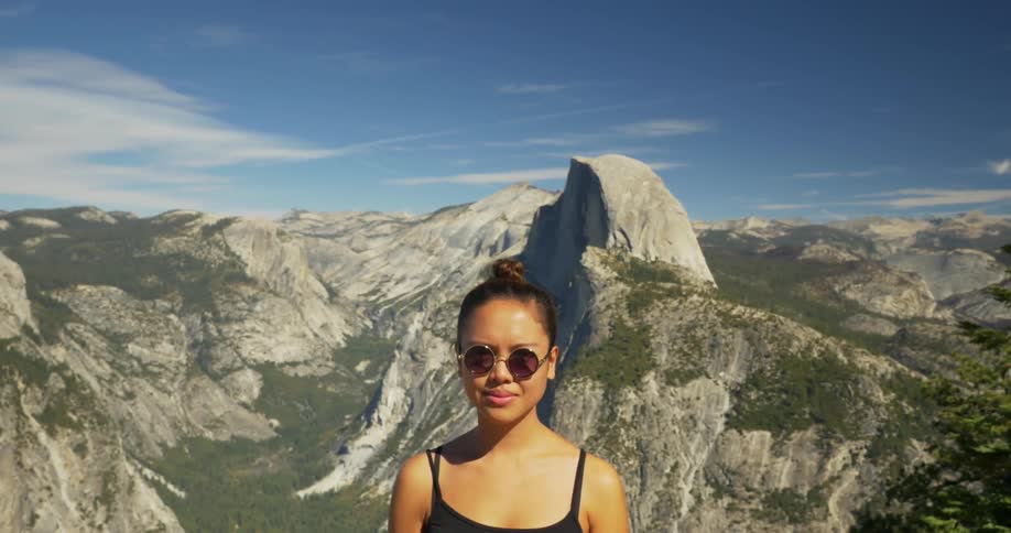 A woman stands in front of a mountain range