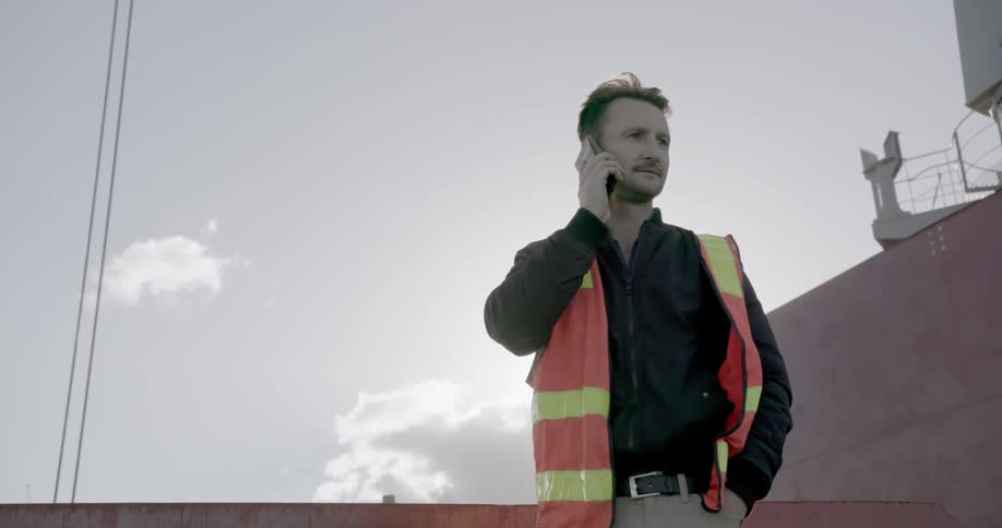A man in a safety vest is talking on his cell phone