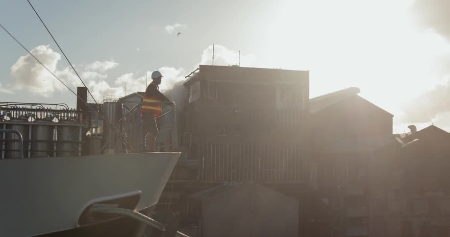 A construction worker leans on the rail of a large ship