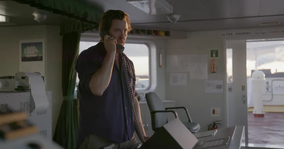 A man stands and talks on the phone on ships bridge