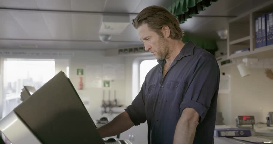 A man is standing in front of a computer looking at the screen