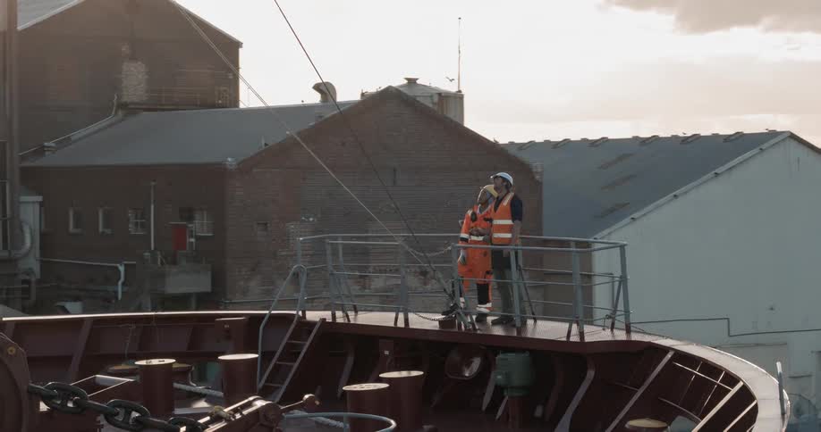 Two men stand on a ship and one points upwards