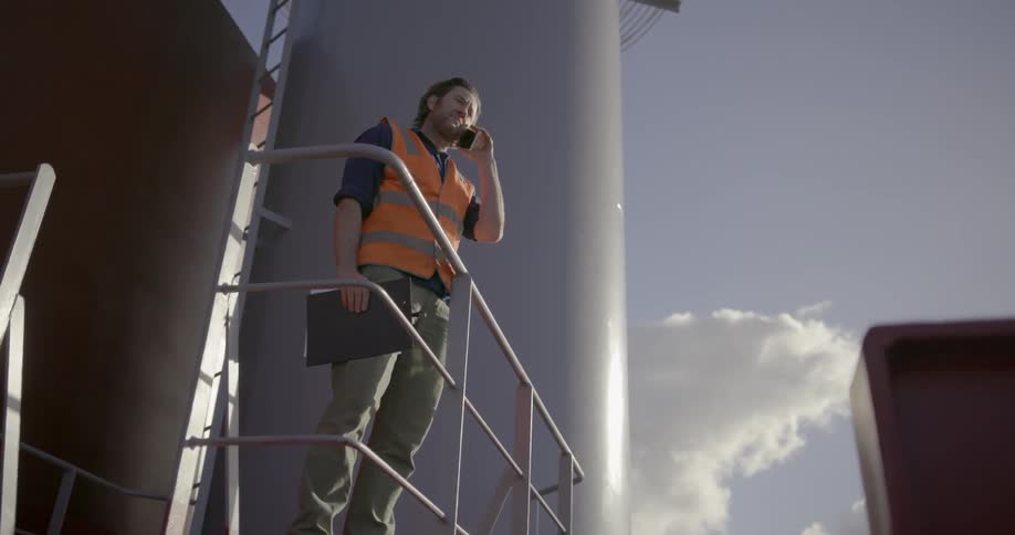 Man stands next to a railing talking on a phone