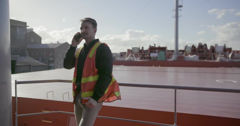 A man in an orange vest talks on the phone
