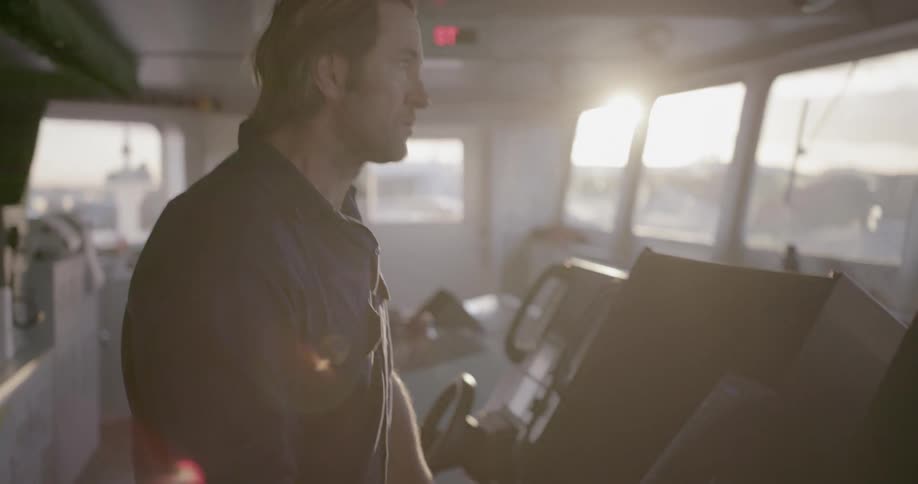 A man uses controls on the bridge of a ship