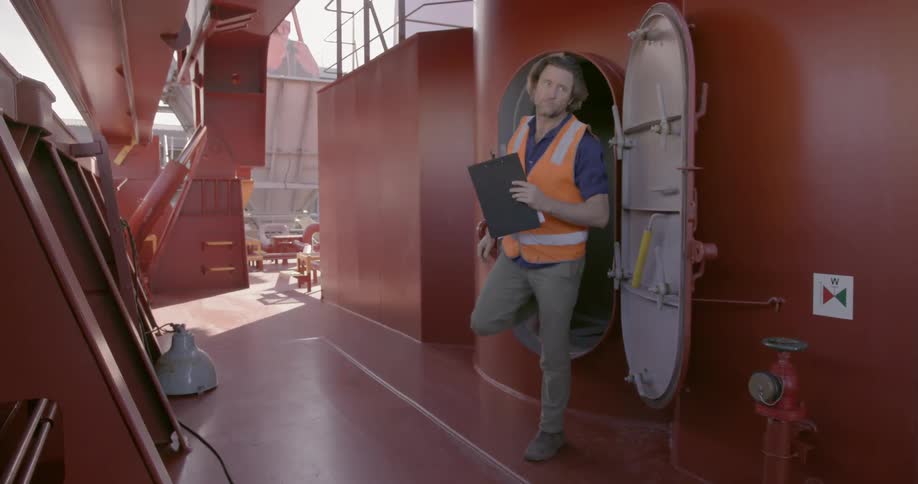 Man climbs out of an area of a ship and walks on deck