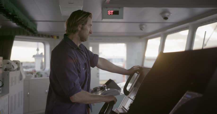 A man holds the wheel on a ships bridge