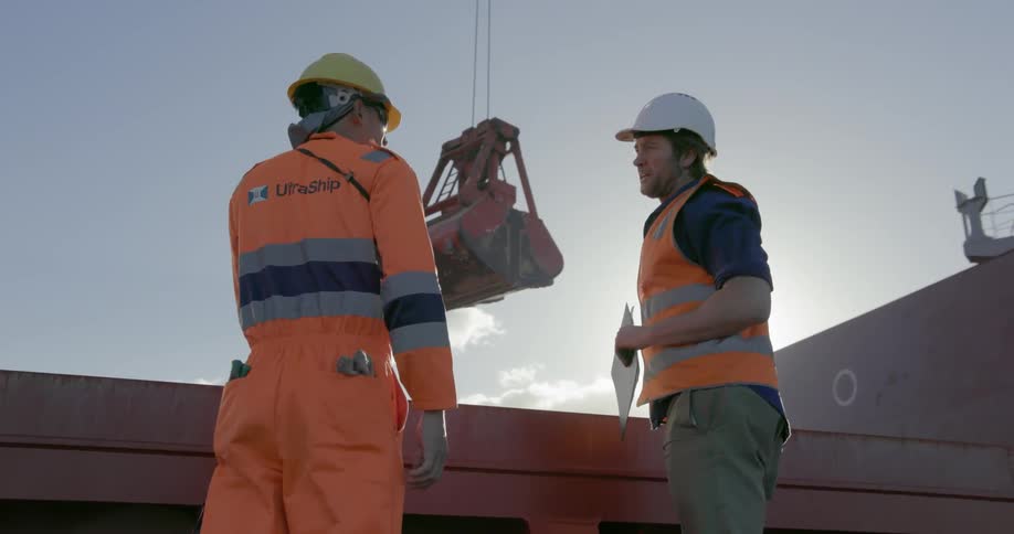 Two construction workers talk near a crane