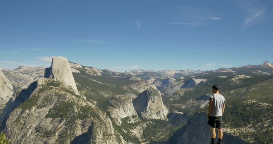 Man stands on a mountain taking in the view on a sunny day