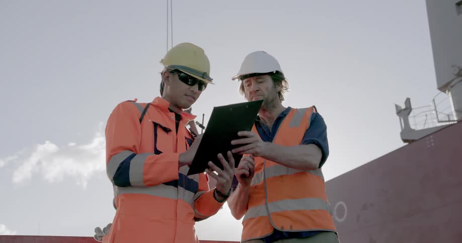 Two construction workers signing a clipboard