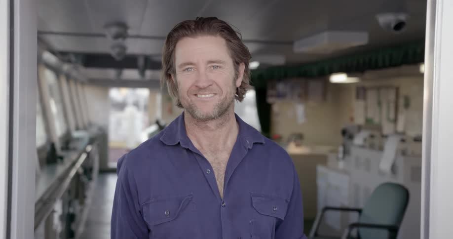 Man smiles while standing on a ship