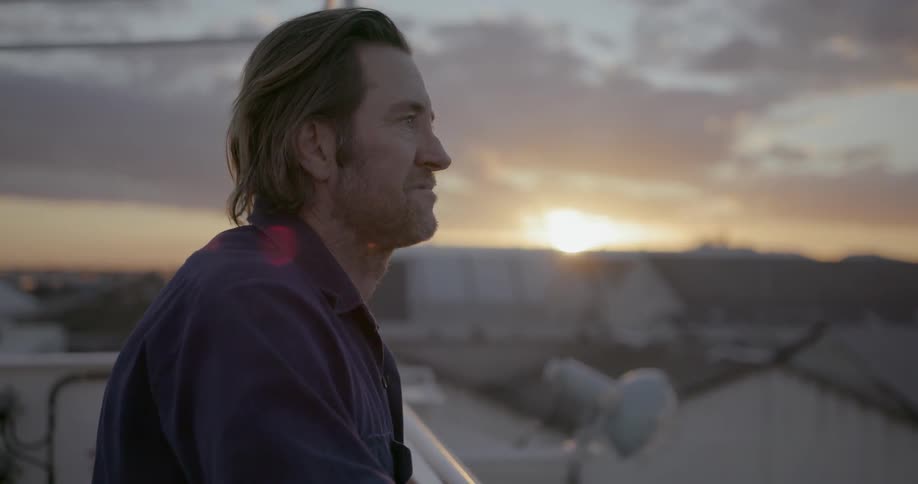 Man looks at city buildings at sunset