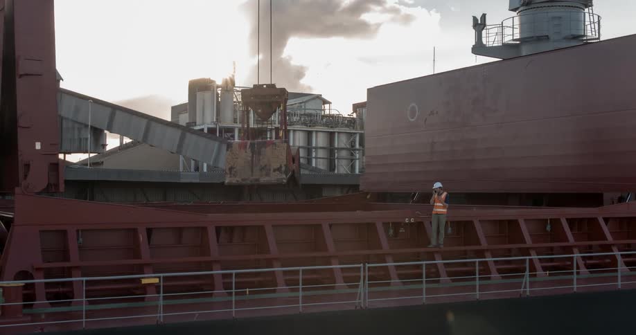A man stands on a ship while a crane is lowered down