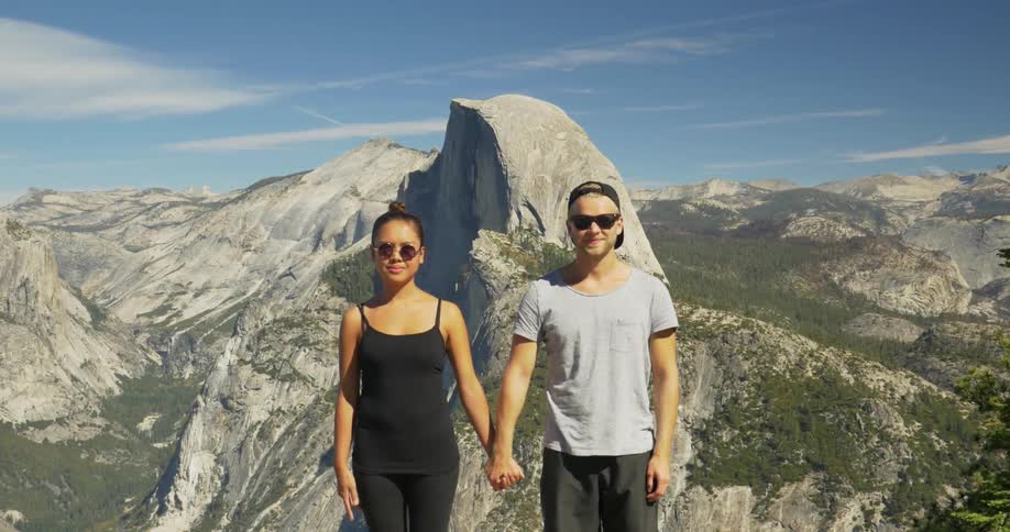 A man and woman holding hands while standing near rocky hills