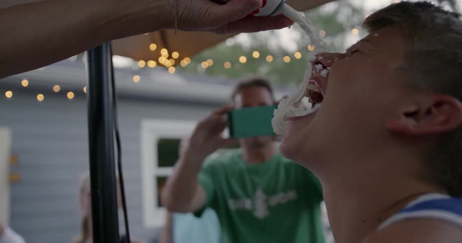 Someone is spraying whipped cream all over a kids face at a party