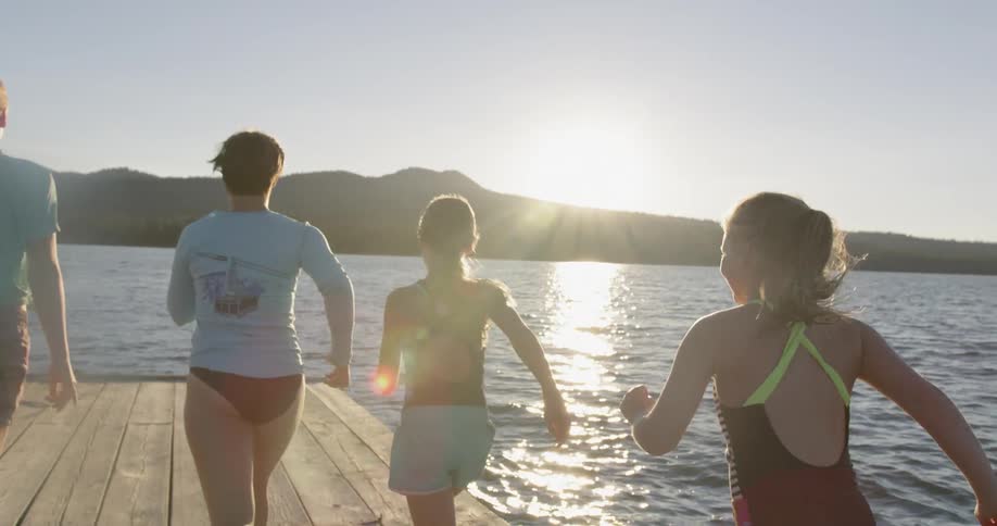 A group of girls run towards the end of a pier on a sunny day