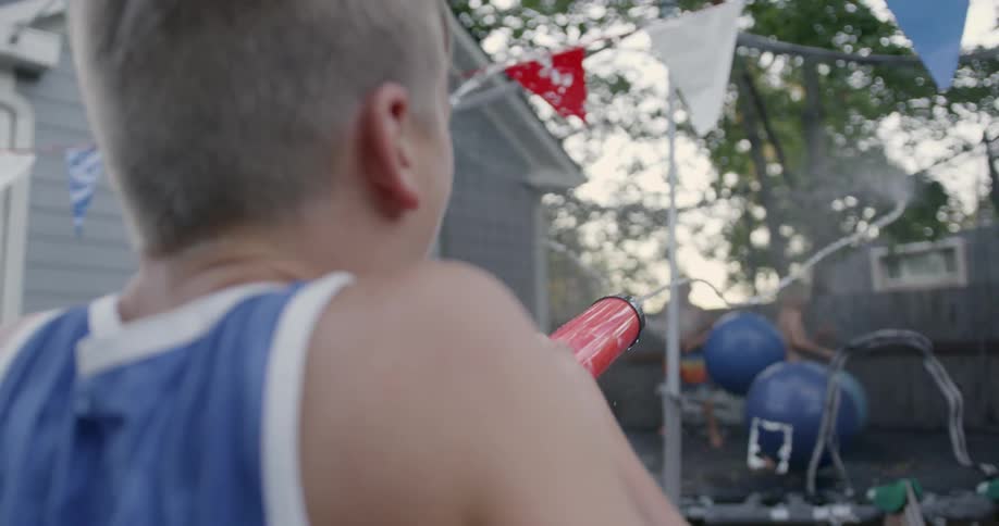 Kids are shooting water guns at bouncing balls in the distance